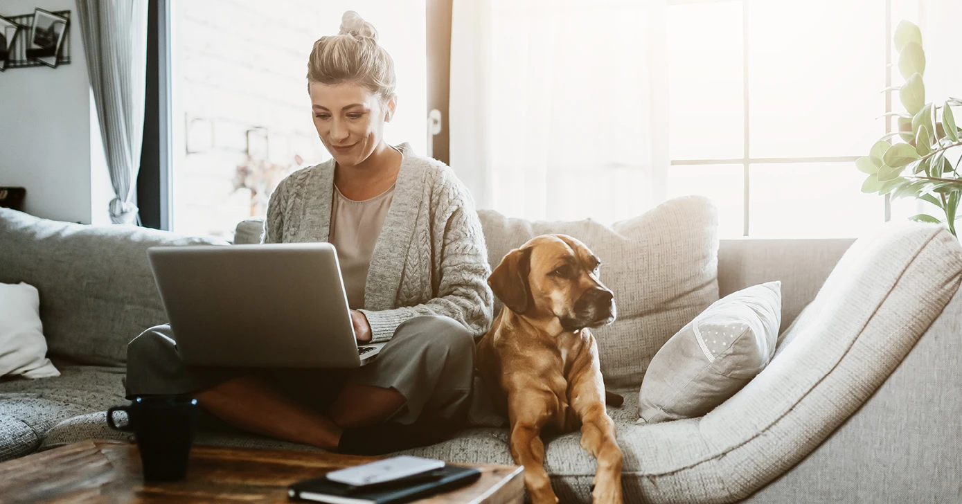 Woman on laptop with dog sitting next to her