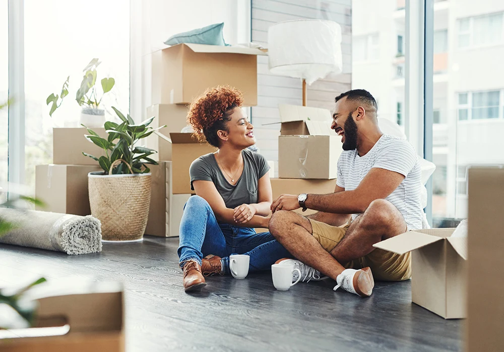a couple sitting on the floor with moving boxes