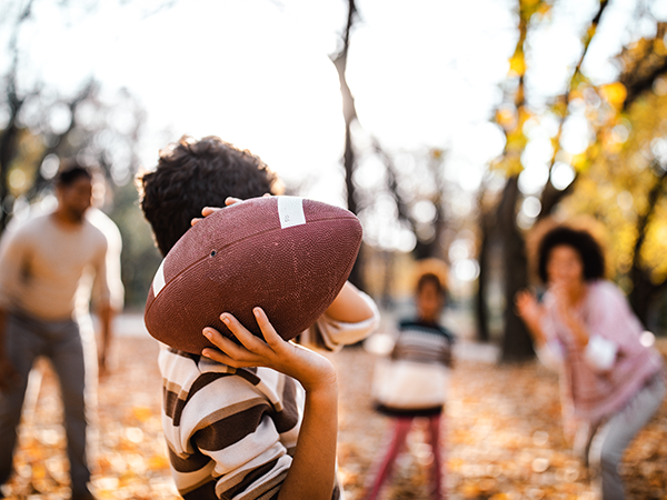 Family playing football outside in the fall leaves