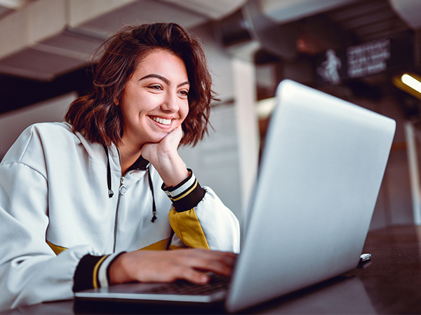 Female college graduate looking at ways to repay student loans on laptop