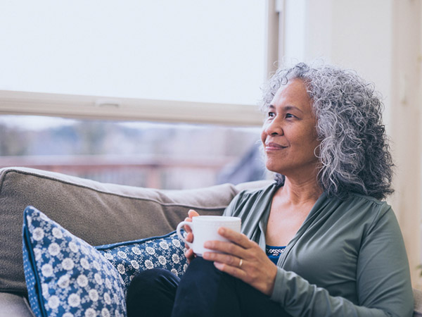 Woman drinking coffee on the couch looking out the window