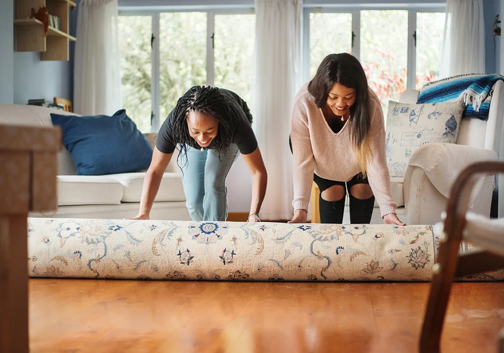 Two Women Rolling Out a Rug