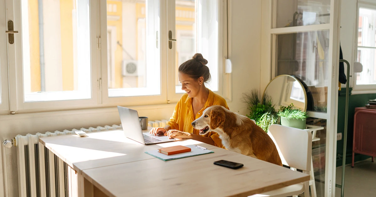 Woman on laptop next to dog